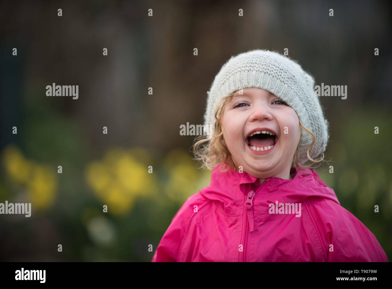 Petite fille rire dans Spring garden avec chapeau Banque D'Images