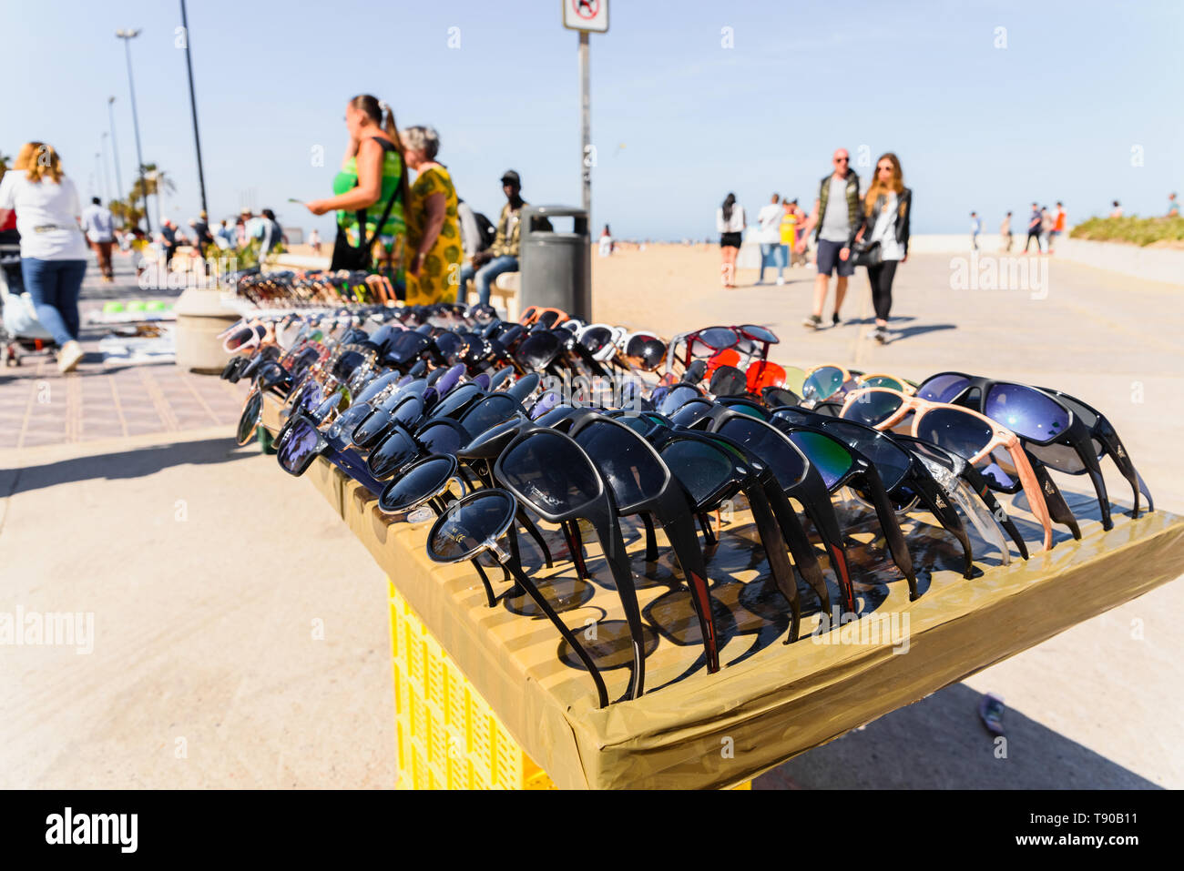 Valencia, Espagne - 12 mai 2019 : les immigrants illégaux de vendre de fausses lunettes et des souvenirs aux touristes sur la plage de Valence. Banque D'Images