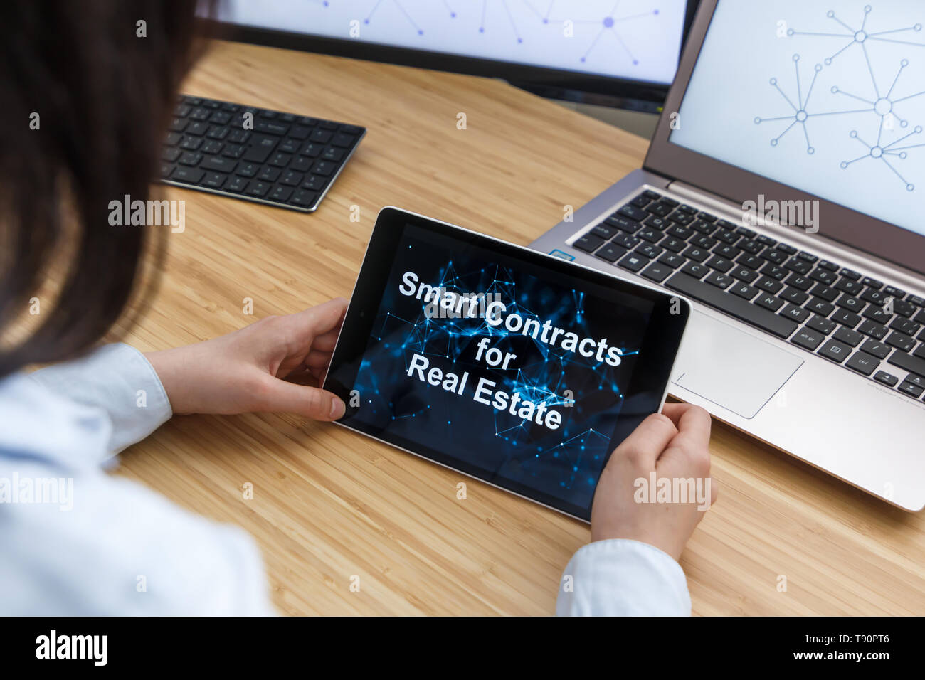 Femme d'affaires à l'aide de Smart Contrats pour l'immobilier. Illustration de l'Ethereum Blockchain sur l'écran du Tablet PC, et l'ordinateur portable. Banque D'Images