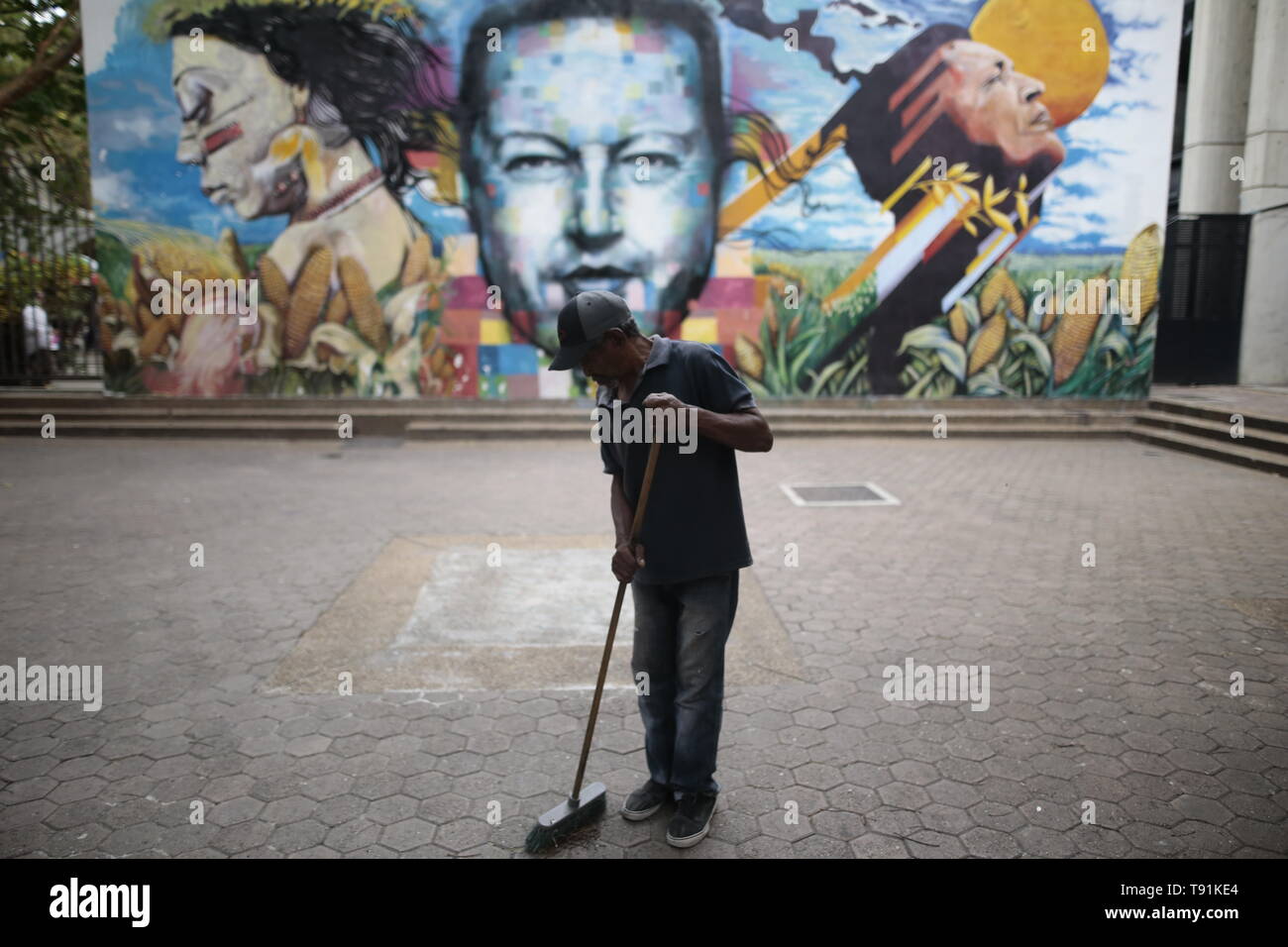 13 mai 2019, Venezuela, Caracas : Alain Jose Kei, 77 ans balaie devant une fresque avec l'image de feu le Président Hugo Chavez. Comment est-il affecté par la crise économique ? 'Nous ne sont jamais payés en totalité. La banque ne s'est jamais passe tout sur nous, dit le Street Sweeper, qui a travaillé dans ce domaine pendant sept ans. En dépit de la situation, Alain reste optimiste. 'J'ai l'impression qu'il allait mieux. Et je vais continuer à travailler parce que je ne veux pas perdre ce travail," dit-il. Le Venezuela a été dans une profonde crise économique depuis des années. Dans un index, le pays classé 188 sur 1 Banque D'Images
