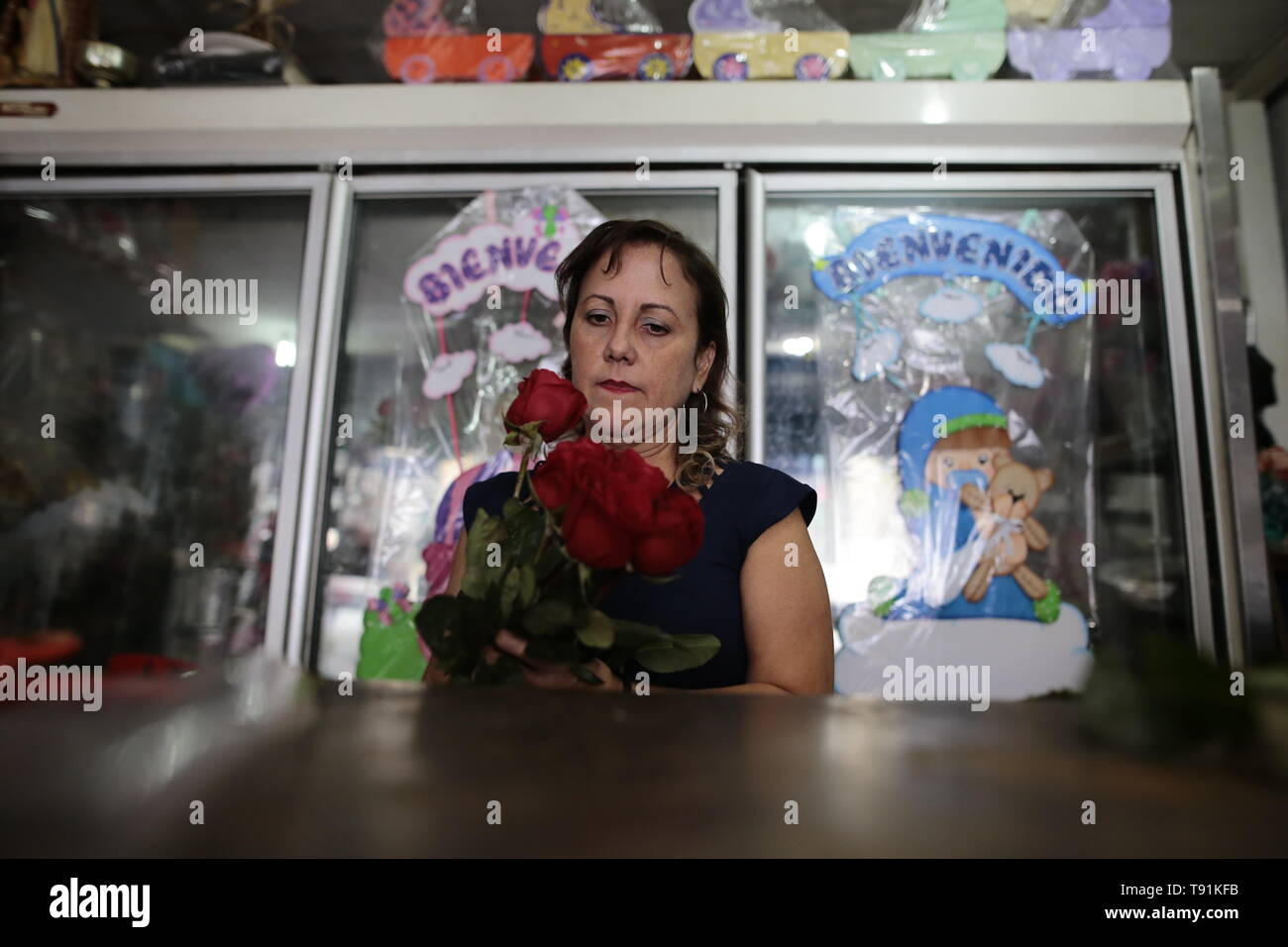 13 mai 2019, Venezuela, Caracas : Yuritza Morales, ancien professeur et maintenant, marchande de fleurs, prépare un bouquet de roses. La petite entreprise familiale est de ressentir les effets de la crise économique, dit Yuritza. "L'autre jour était la fête des Mères. Nous avons vendu environ moitié moins que nous avons fait il y a trois ans, dit le 42-year-old. "Mais je n'ai jamais pensé à émigrer. En plus, j'ai le lupus. Il serait certainement difficile de trouver un emploi ailleurs dans ces circonstances. Et je n'ai pas pris de médicament dans deux ans parce qu'ils sont très rares ici. Dieu merci, je me sens bien', la vendeuse décrit sa situation Banque D'Images