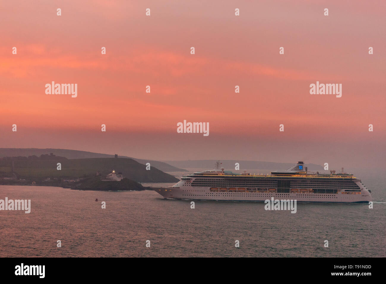 Athelstan, Cork, Irlande. 16 mai, 2019. Une aube rouge accueille le Royal Caribbean Cruise ship Brilliance of the Seas comme elle fume devant le phare Roches Point à l'aube, sur sa façon de visiter la ville historique de Cobh, dans le comté de Cork, Irlande. Crédit : David Creedon/Alamy Live News Banque D'Images