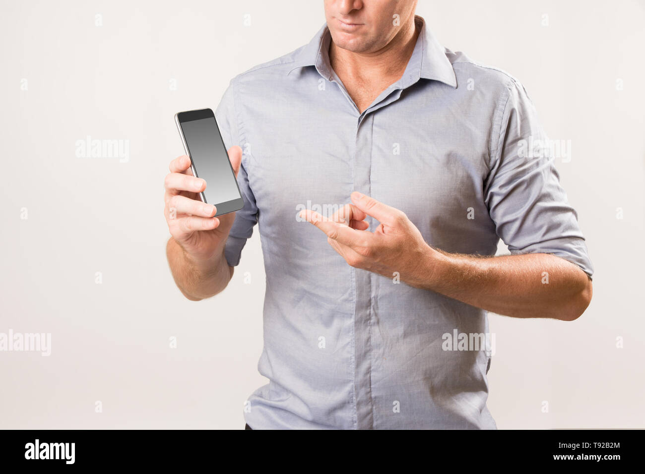 Man holding phone et pointant sur l'écran à l'autre part - la vie moderne / concept de droit des télécommunications. Banque D'Images