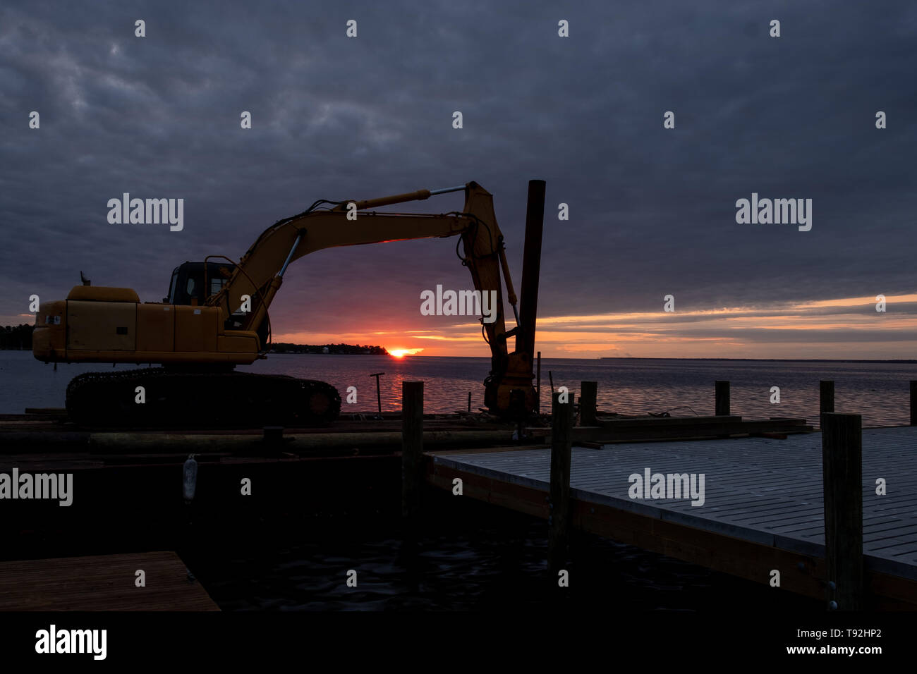 Une pile driver repose sur une plate-forme flottante par une jetée après avoir été utilisés pour aider à restaurer des dommages-intérêts à l'ouragan Florence. Lever du soleil en arrière-plan. Banque D'Images