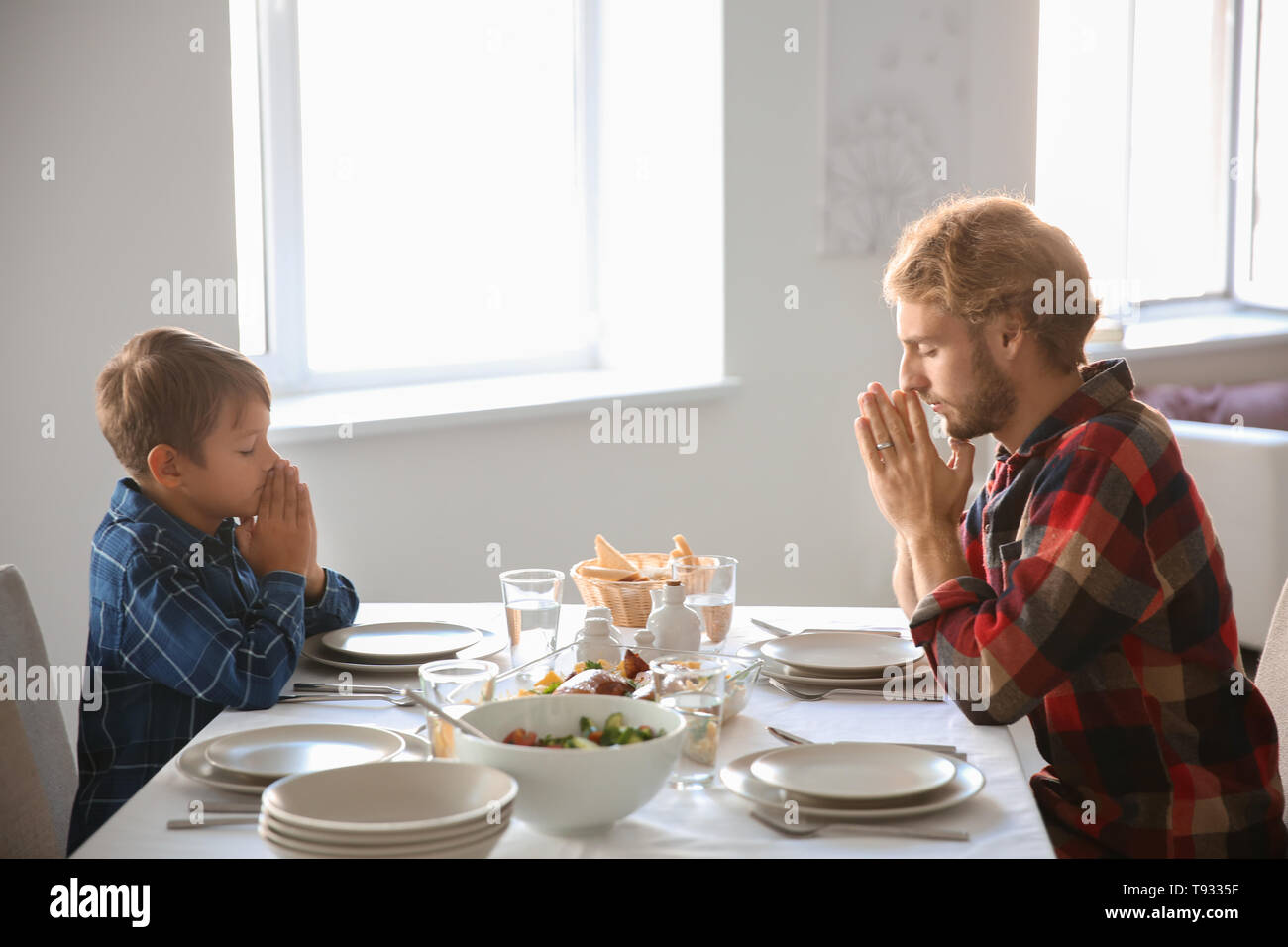 Avec Père Fils priant avant repas à la maison Banque D'Images