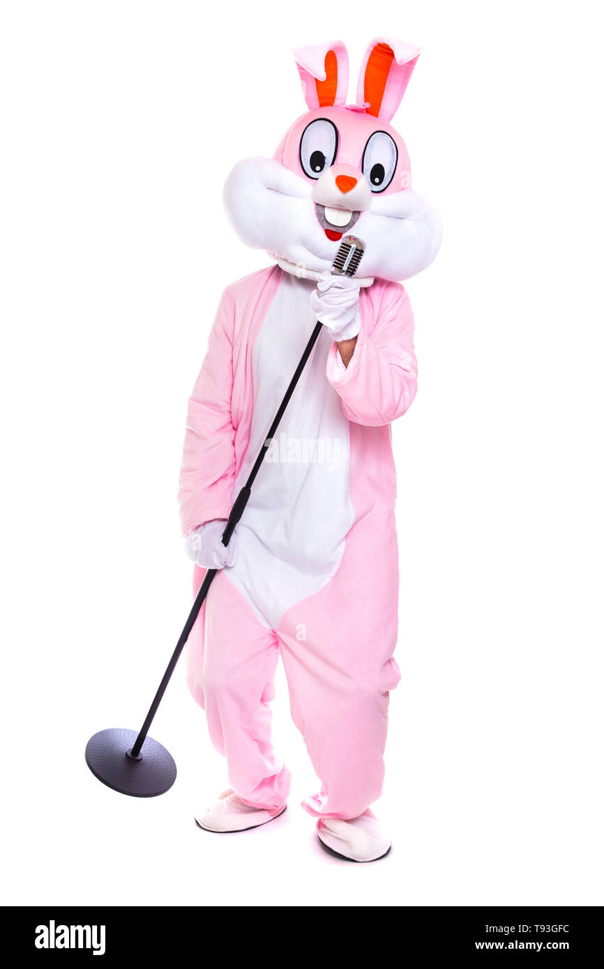 Lapin de Pâques en peluche grandeur nature chante en rétro microphone, fête de Pâques, danse sur fond blanc. Drôle, heureux singer, musicien, lapin ou lièvre Banque D'Images