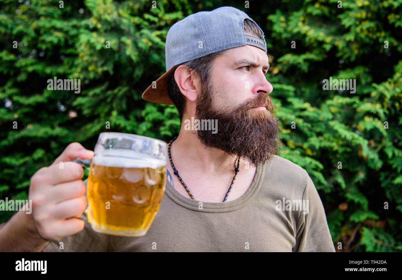 Culture potable. Hipster holding beer mug. Hipster barbu de boire une bière sur la nature de l'été. Hipster buveur. Homme Hipster avec craft beer. L'homme brutal avec les habitudes de consommation. Boire que de la bière forte. Banque D'Images