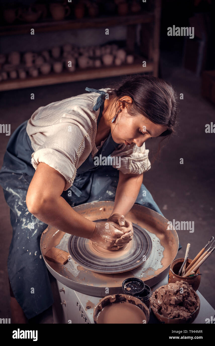Charmante femme artisan crée un nouveau à partir de l'argile de poterie sur un tour de potier. De l'artisanat folklorique. Banque D'Images