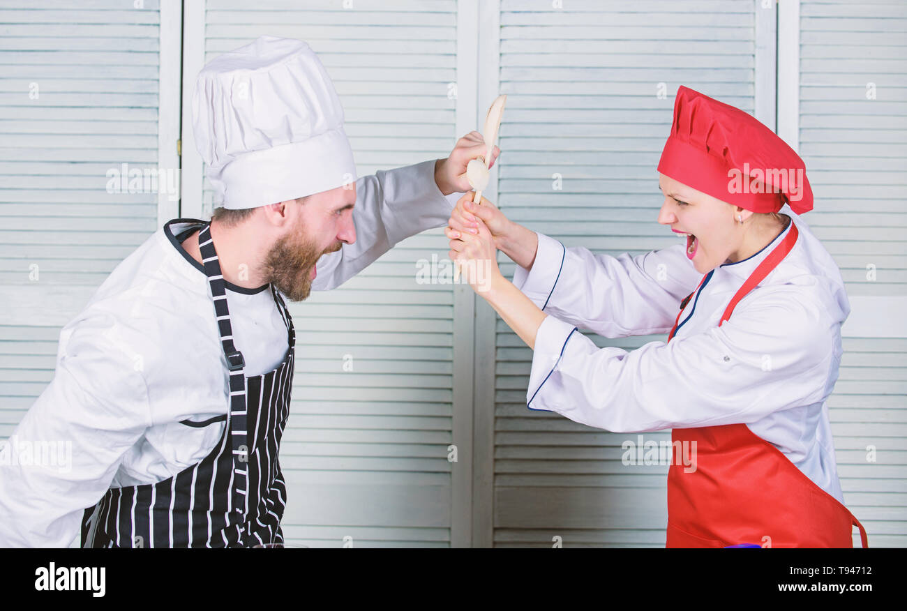 Couple en compétition en arts culinaires Cuisine règles. Qui mieux cuisiner. Bataille culinaire concept. Femme et homme barbu show culinaire concurrents. Cuisine ultime défi. Bataille de deux chefs culinaires. Banque D'Images