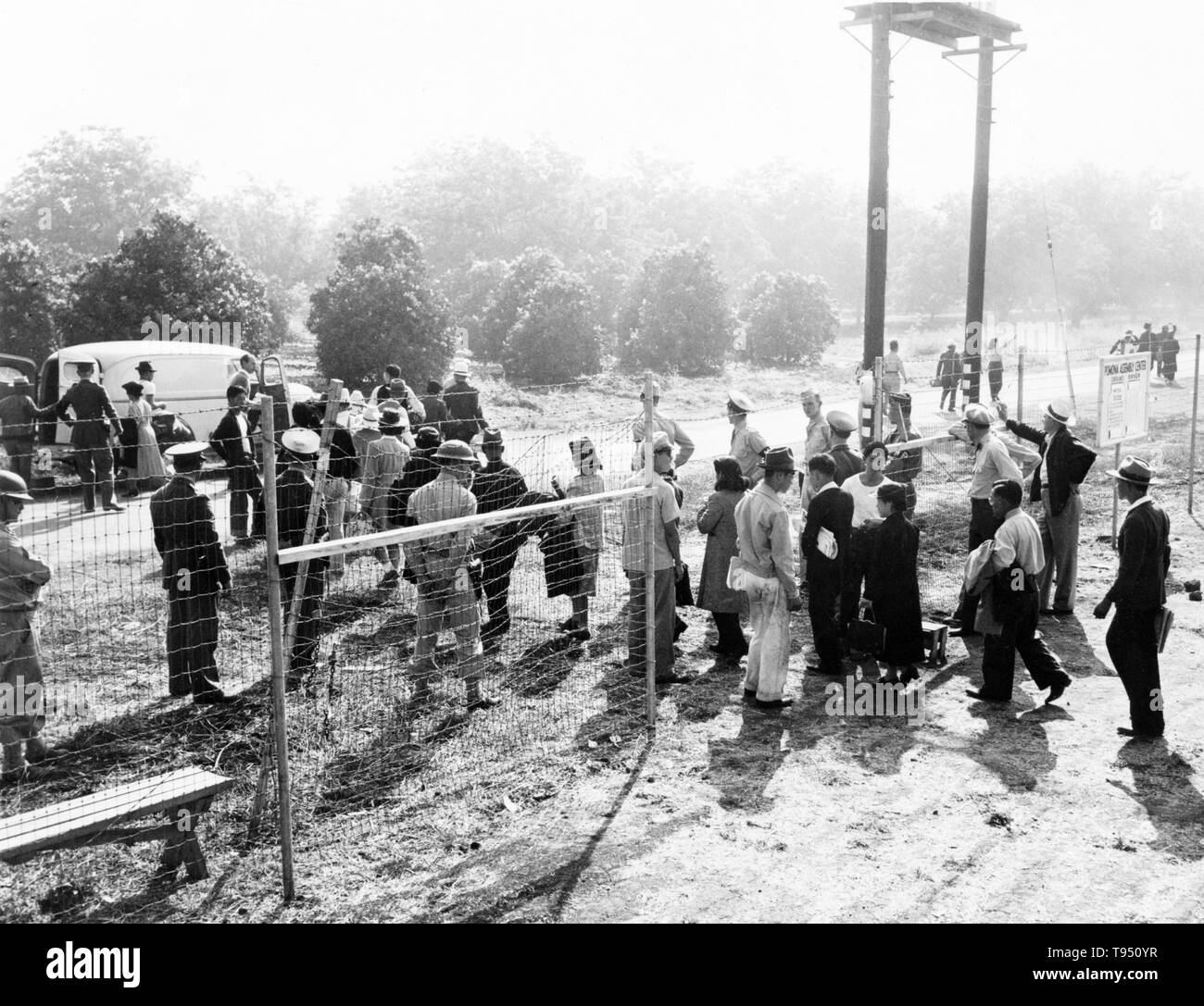 Intitulé : "Les sinistrés passent par déclenchement externe de centre vers les bus en attente de réinstallation pour les amener au centre." L'internement des Américains d'origine japonaise pendant la DEUXIÈME GUERRE MONDIALE ont la réinstallation forcée et d'incarcération dans des camps de 110,000-120 000 personnes d'origine japonaise (62  % des internés étaient citoyens américains) commandé par le président Roosevelt peu après le Japon attaque sur Pearl Harbor. Américains ont été incarcérés en se fondant sur les concentrations de population locale et la politique régionale. Banque D'Images