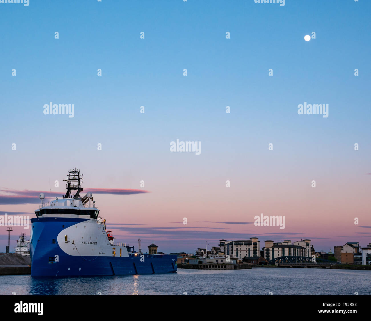 Leith Docks, Edinburgh, Ecosse, Royaume-Uni, 16 mai 2019. Météo France : un ciel clair coloré crépuscule sur le port de Leith avec un navire d'approvisionnement à l'étranger appelé NAO Fighter dans le port illuminé par les derniers rayons du soleil avec une presque pleine lune brillante dans le ciel bleu Banque D'Images