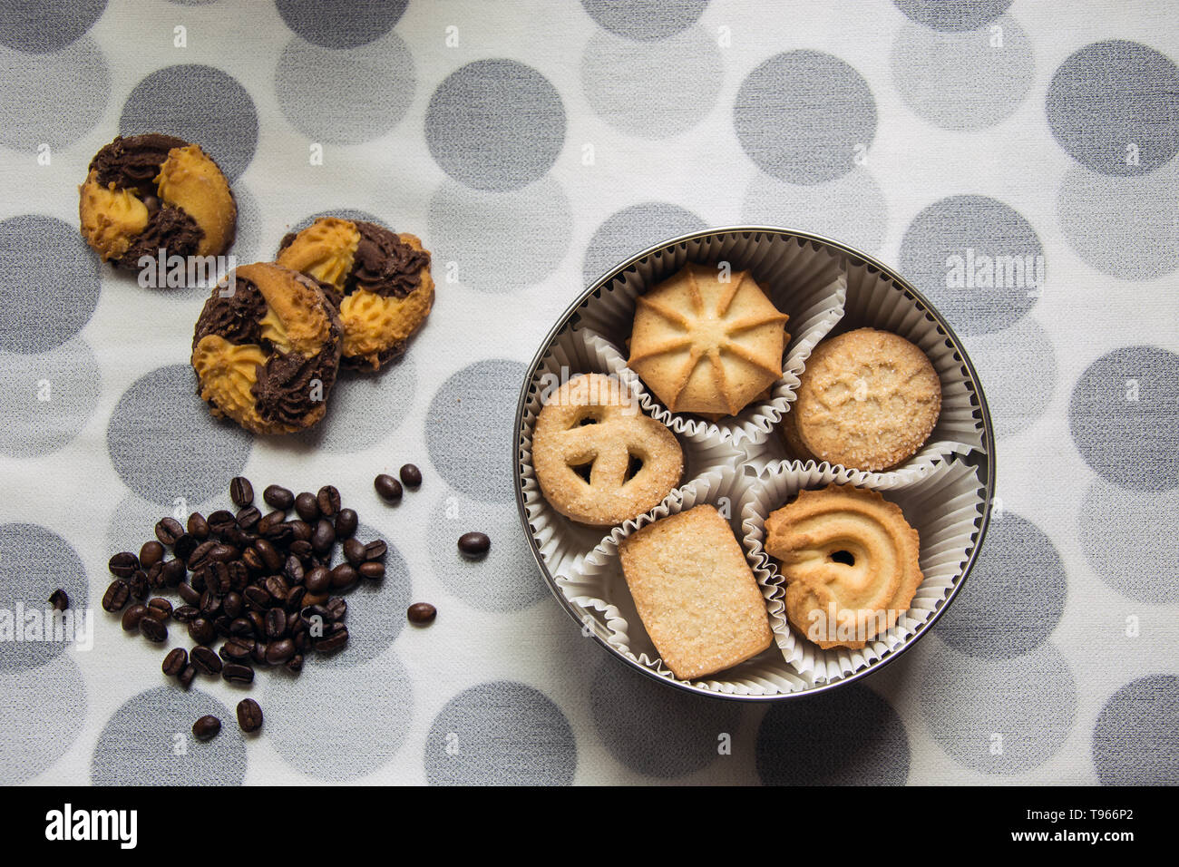 Des biscuits avec le sucre dans une boîte ronde et trois avec les grains de café sur une nappe à pois Banque D'Images