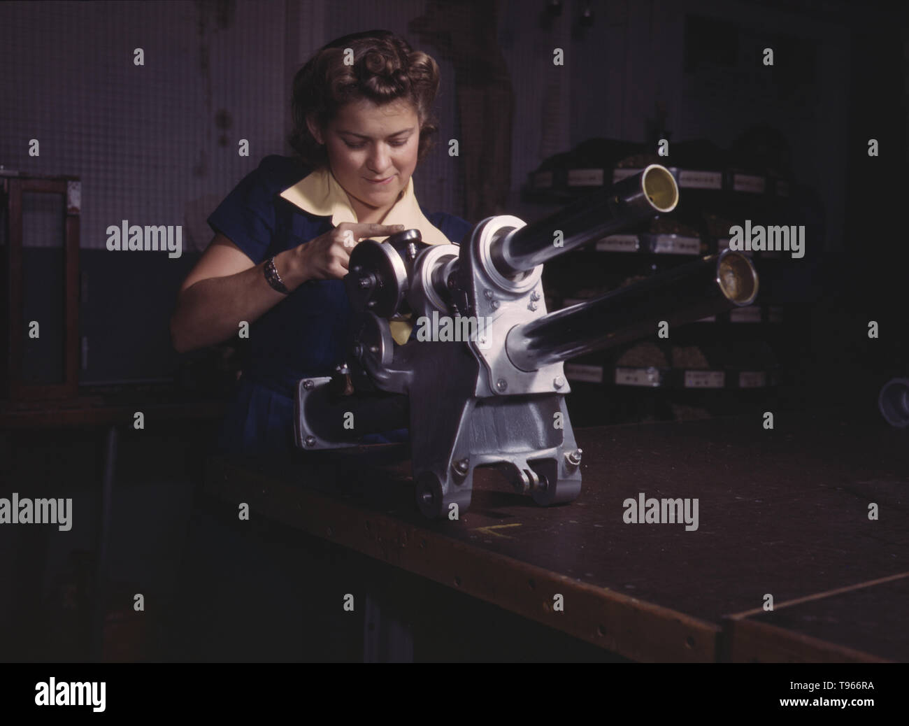 Une jeune femme employée de North American Aviation, Incorporated, travaillant sur le mécanisme d'atterrissage d'un avion de chasse P-51, Inglewood, Californie. Le mécanisme ressemble à un petit canon. Bien que l'image de l' 'Rosie Riveter reflète le travail industriel de soudeurs et riveter, la majorité des femmes qui travaillent en usine non rempli des postes dans tous les secteurs de l'économie. Ce qui unifiait les expériences de ces femmes était qu'elles étaient elles-mêmes, et le pays, qu'ils pourraient faire un travail d'homme et pourrait bien le faire. Photographié par Alfred T. Palmer, 1942. Banque D'Images