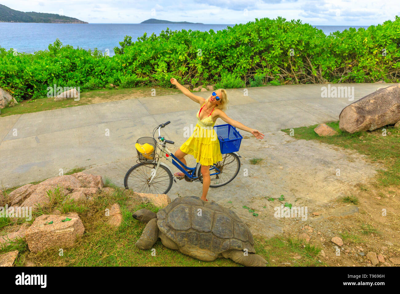 Happy young woman on touristiques vie location près de Anse Banane dans La Digue, Seychelles, Aldabra tortue géante, Aldabrachelys gigantea Banque D'Images