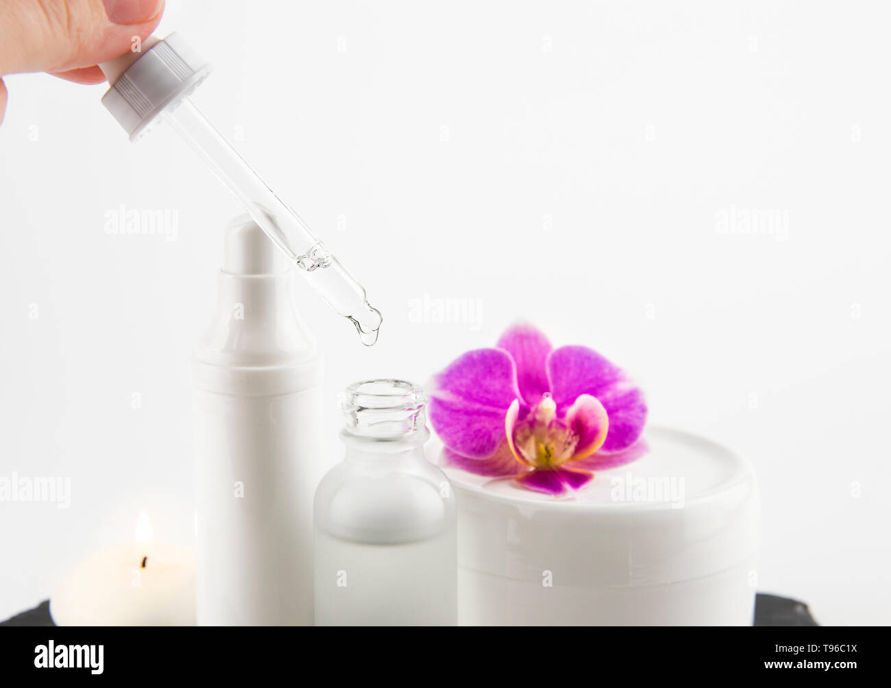 Femme part prendre de l'acide hyaluronique ou collagène liquide à la pipette à partir de la bouteille de verre, pots de crème sur l'arrière-plan, selective focus on compte-gouttes et liquides Banque D'Images