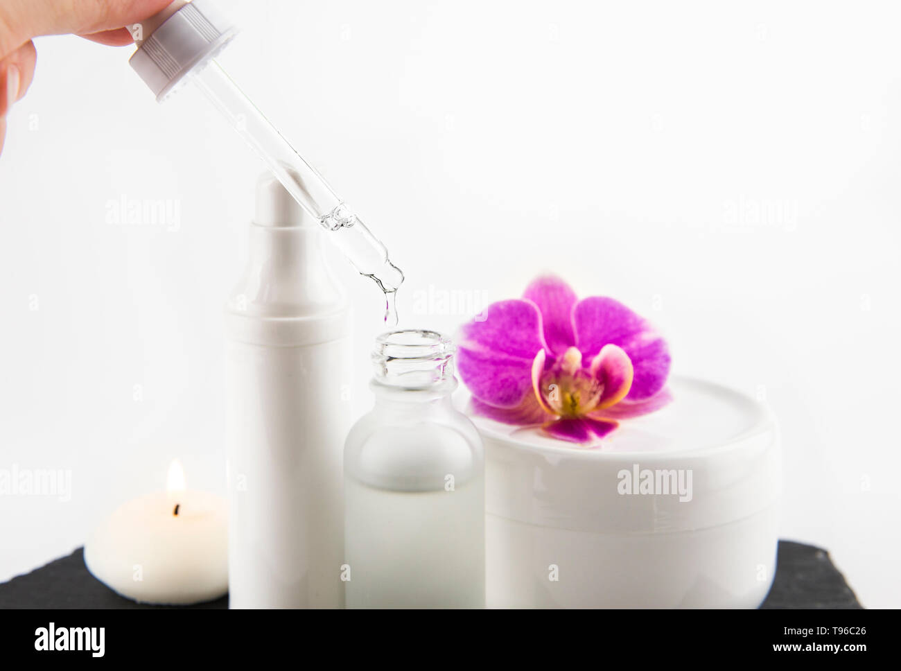 Femme part prendre de l'acide hyaluronique ou collagène liquide à la pipette à partir de la bouteille de verre, pots de crème sur l'arrière-plan, selective focus on compte-gouttes et liquides Banque D'Images