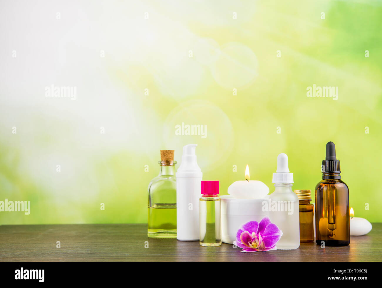 La composition avec beaucoup de différentes tailles, formes et matériaux beauté cosmétiques flacons produits arrangement sur table en bois avec green bokeh studio backg Banque D'Images