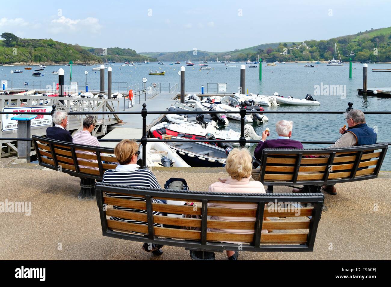 Des gens assis sur des bancs en profitant de la vue sur l'estuaire à Salcombe waterfront sur une journée d'été,Devon England UK Banque D'Images