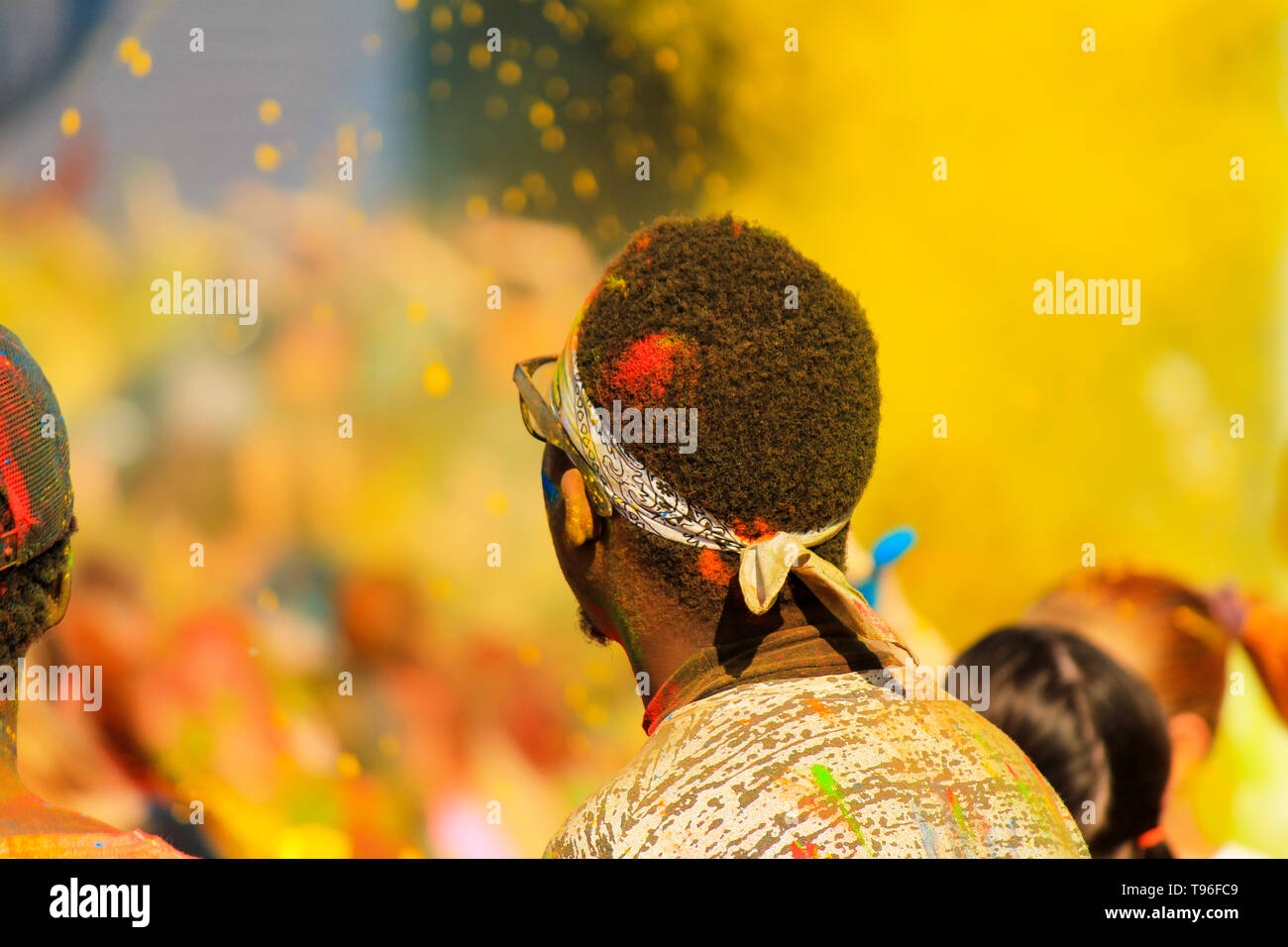 African boy étudiant avec les cheveux couverts de couleur ayant l'amusement dans l'arrière-plan de la peinture jaune au festival Holi au printemps, en été, la ville de Dnipro, Ukraine Banque D'Images