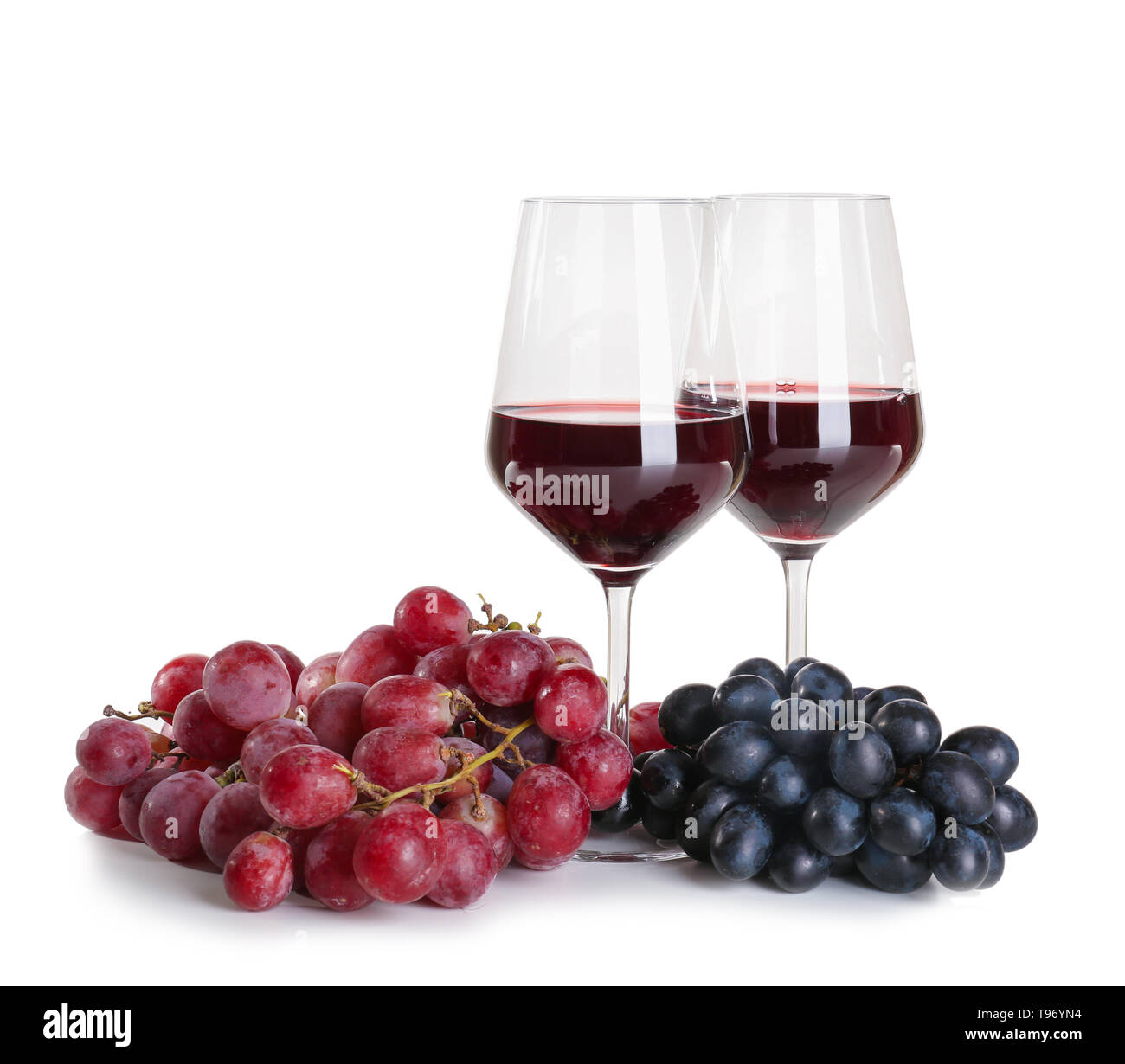 Verres de vin rouge avec des raisins mûrs sur fond blanc Banque D'Images