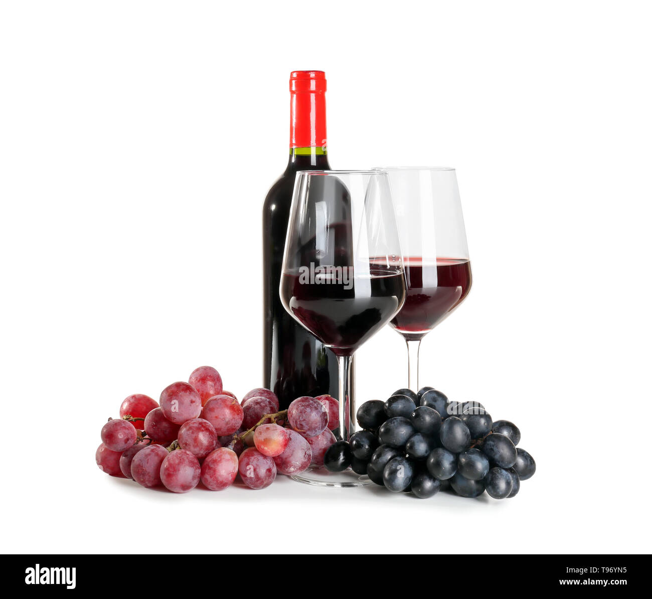 Verres et bouteille de vin rouge avec des raisins mûrs sur fond blanc Banque D'Images