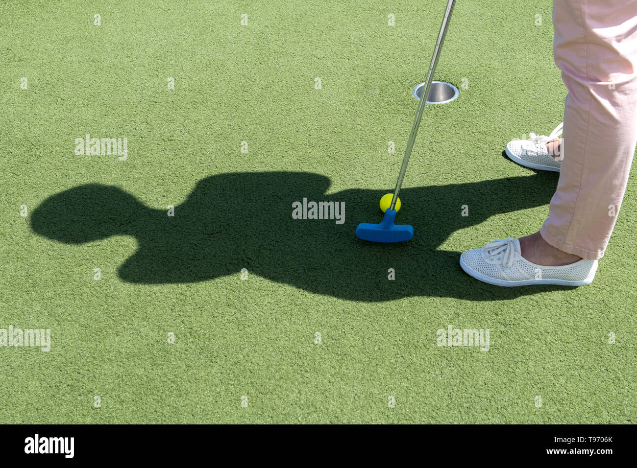 Femme d'âge moyen en jouant au golf sur gazon artificiel Banque D'Images