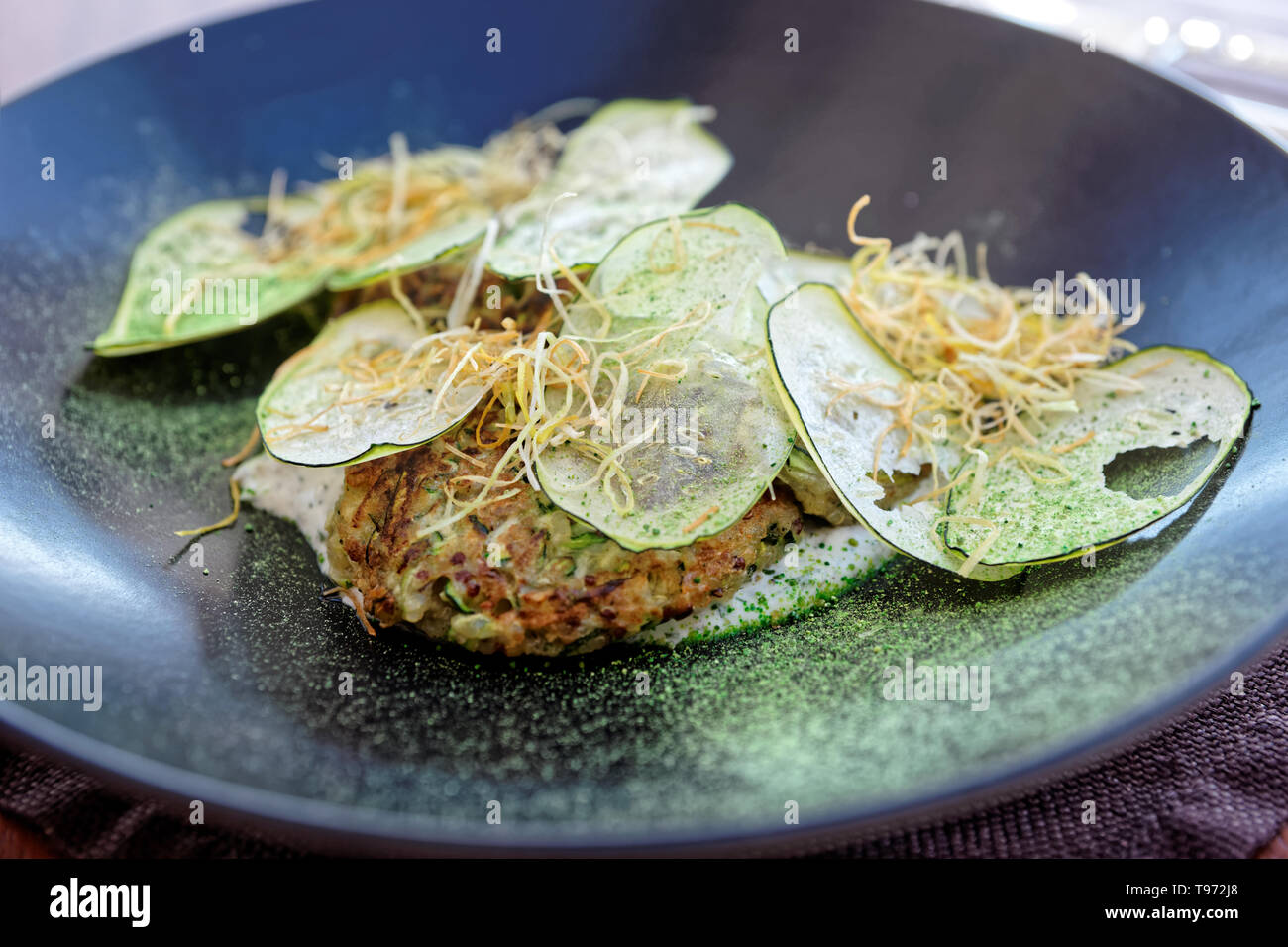 Apéritif végétarien gastronomique créative - zicchini fritter avec les croustilles de légumes ,et l'oignon frit sur la plaque noire Banque D'Images