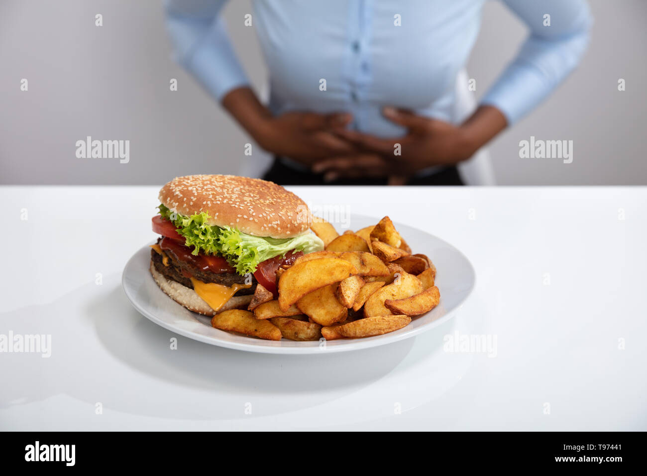Jeune femme souffrant de douleurs à l'estomac pendant le petit-déjeuner Banque D'Images