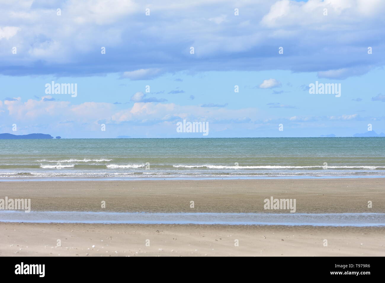 Vue de la plage de sable de couleur brun clair à marée basse avec vue sur la mer de couleur brun-vert, perturbé par les particules de sable en arrière-plan. Banque D'Images