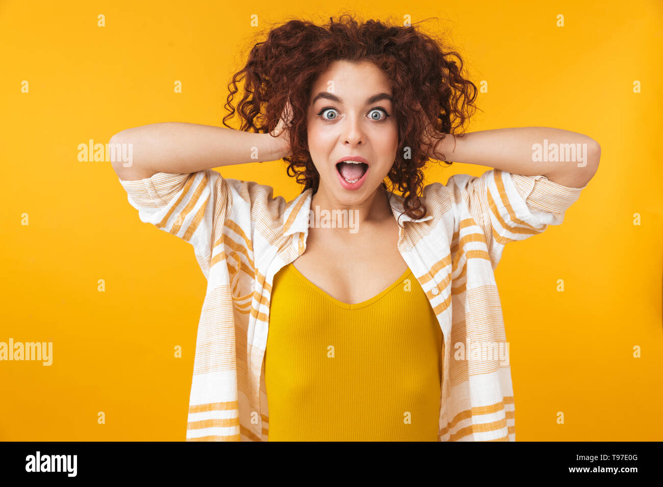 Image de femme excité 20s avec des cheveux bouclés standing and smiling, isolé sur fond jaune Banque D'Images