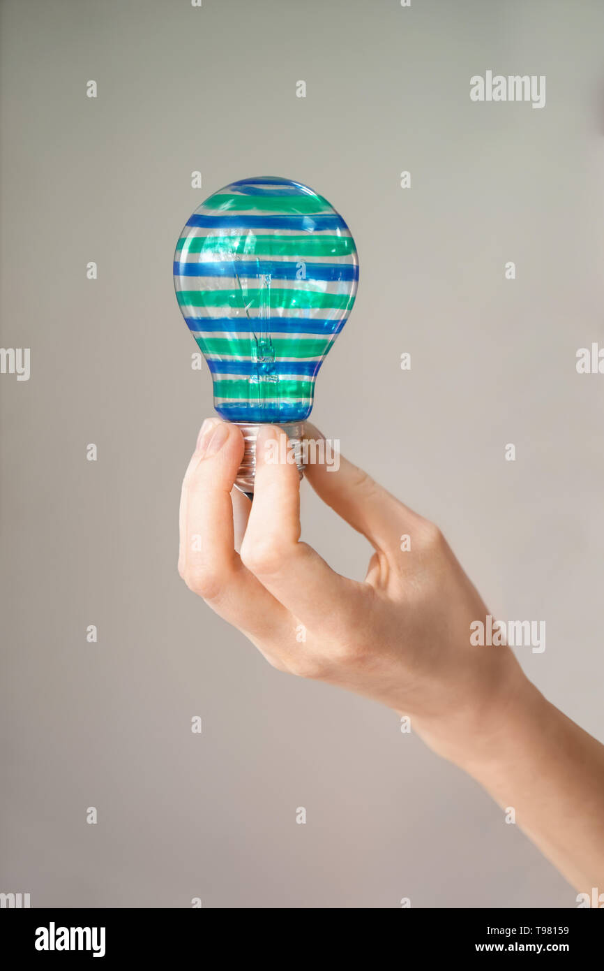 Femme tenant l'ampoule peinte sur fond gris Photo Stock - Alamy