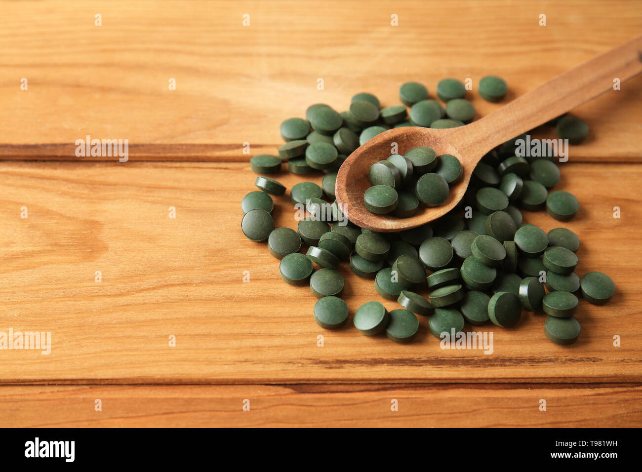 Les comprimés de spiruline avec cuillère sur table en bois Banque D'Images