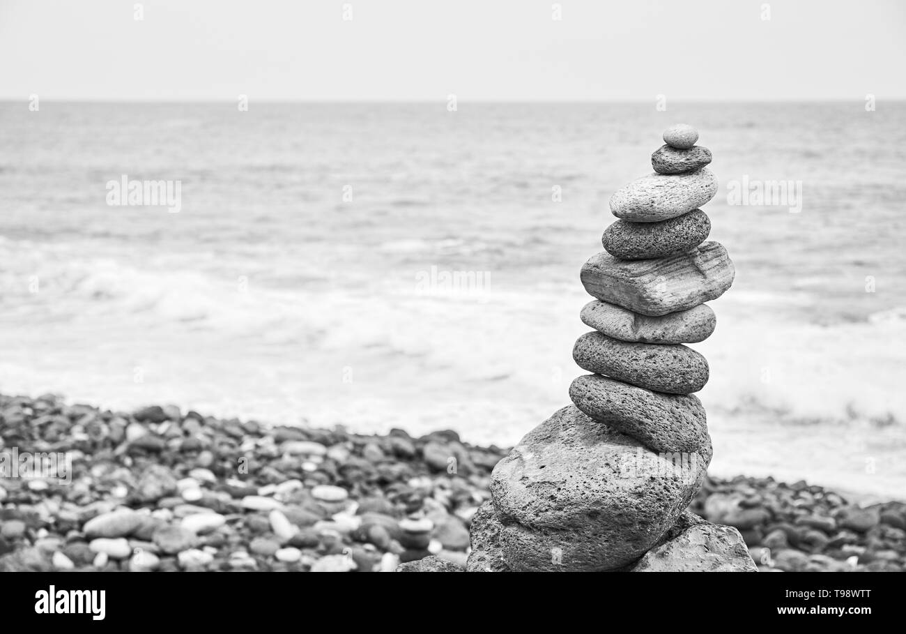 Image noir et blanc d'une pile en pierre sur une plage, selective focus. Banque D'Images