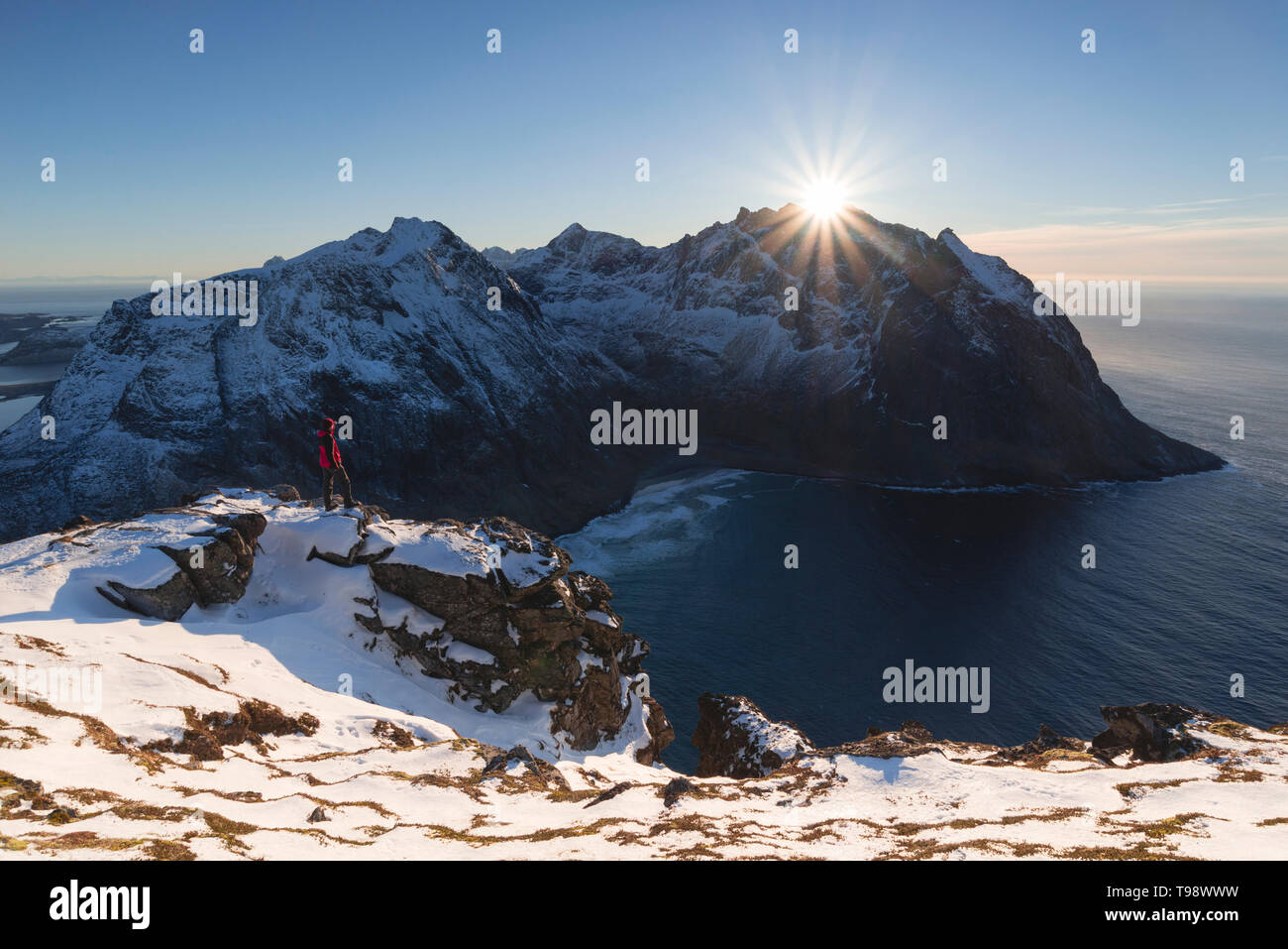Randonneur fait face au soleil juste avant de disparaître derrière le sommet de Kjerringa, Ryten, Lofoten, Nordland, Norvège Banque D'Images