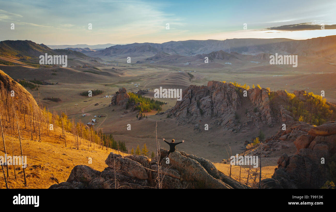 Homme assis sur des rochers avec les bras tendus, le mongol Suisse, désert de Gobi, Mongolie Banque D'Images