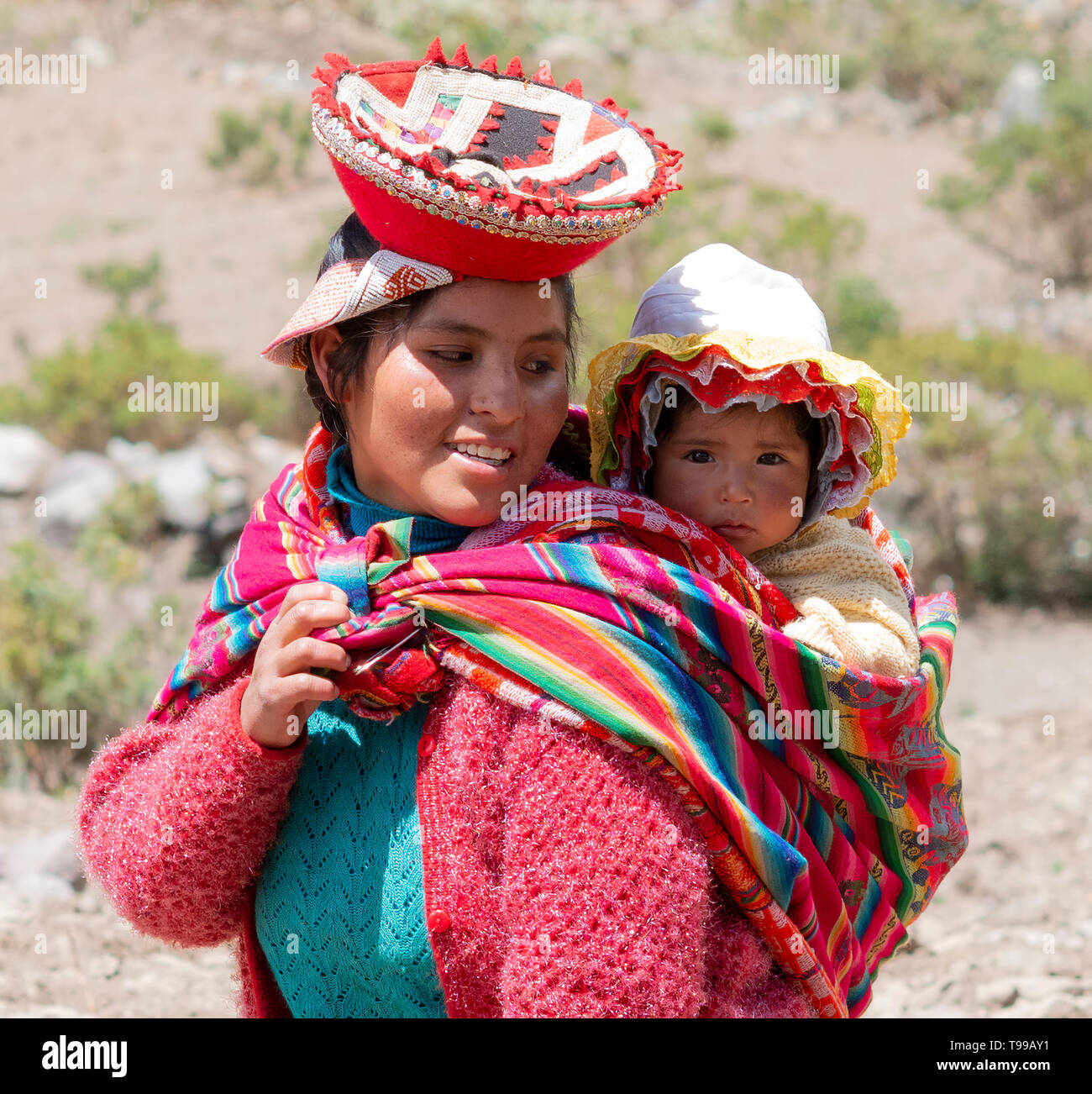 Smiling Femme Quechua habillés en costume traditionnels fabriqués à la main aux couleurs vives et portant son bébé dans une écharpe. 21 octobre 2012 - Patachancha, Cuzco, Pérou Banque D'Images