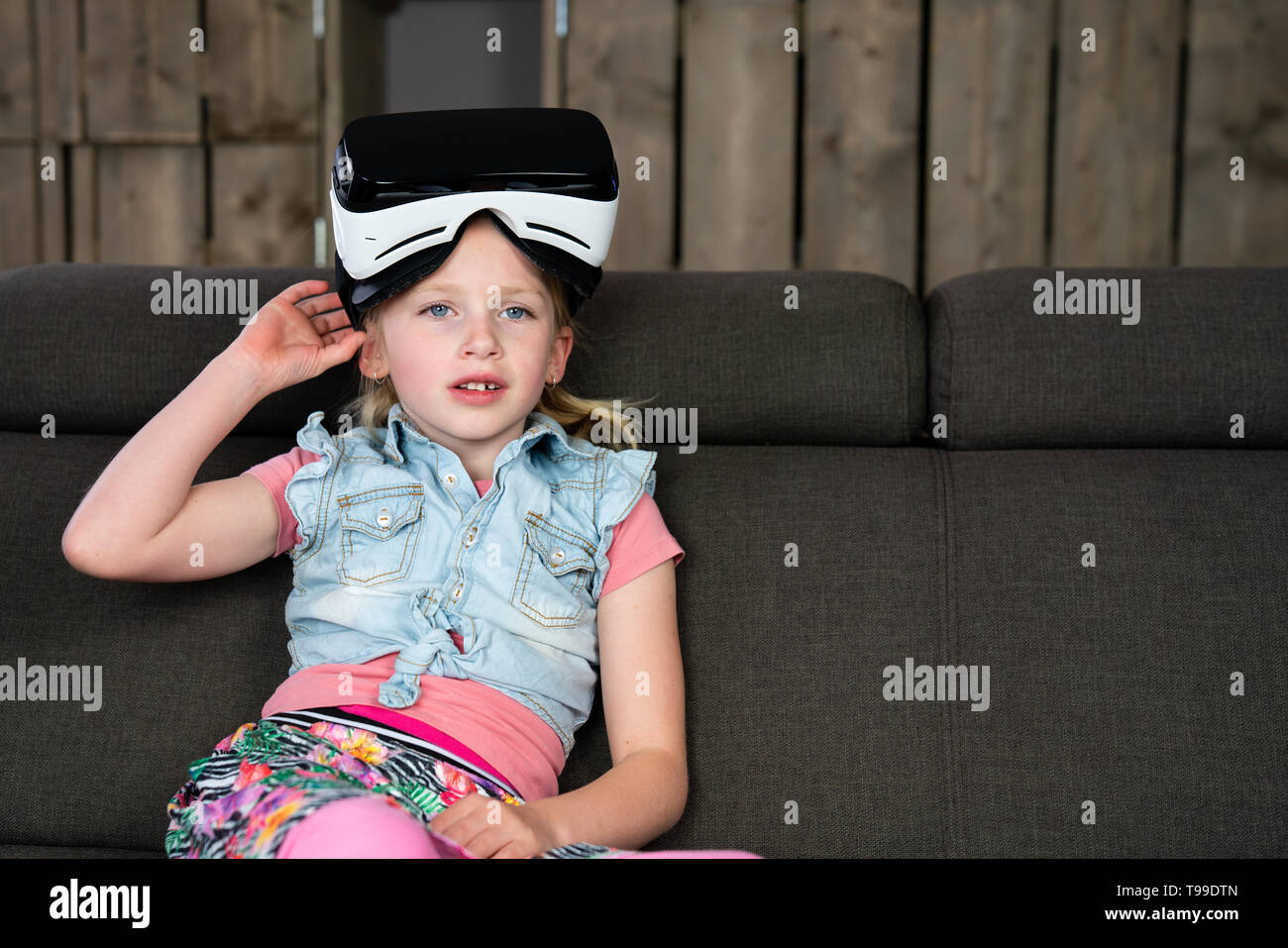 Portrait d'une fille, elle va nous un casque de réalité virtuelle à la maison. Le futurisme au quotidien Banque D'Images