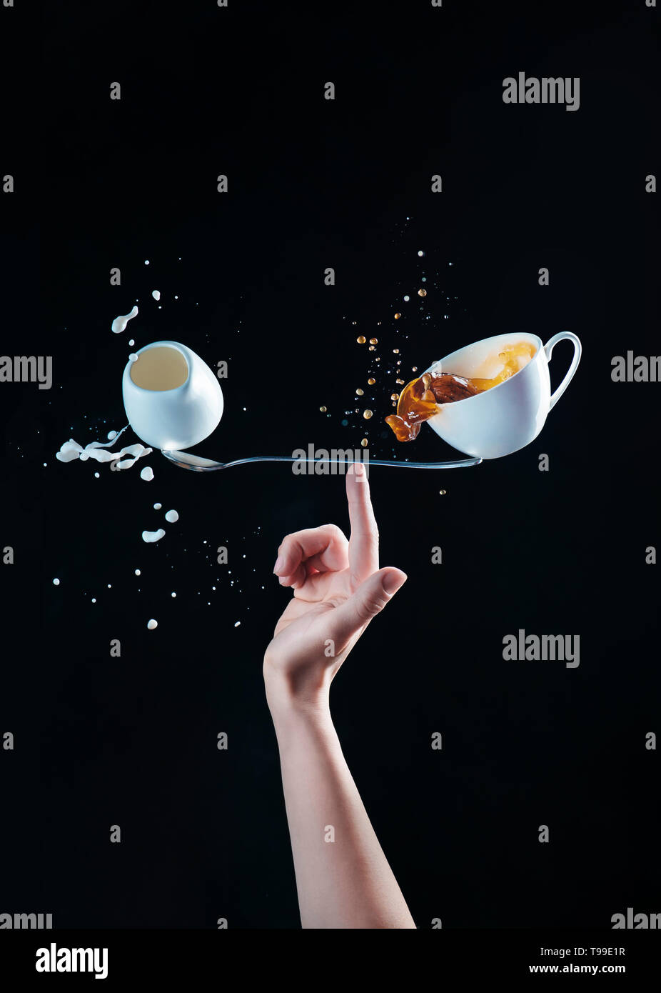 Tasse de café et un petit pichet de lait en équilibre sur une longue cuillère sur le bout des doigts. Un Barista latte équilibré. Café sur un concept créatif Banque D'Images