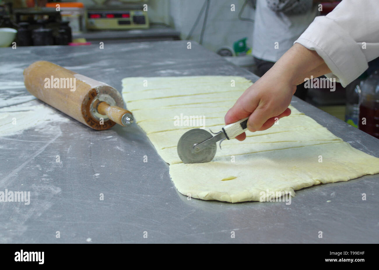 Matières gâteau coupé à la main sur la table. La préparation de la pâte professionnel dans la boulangerie. Banque D'Images