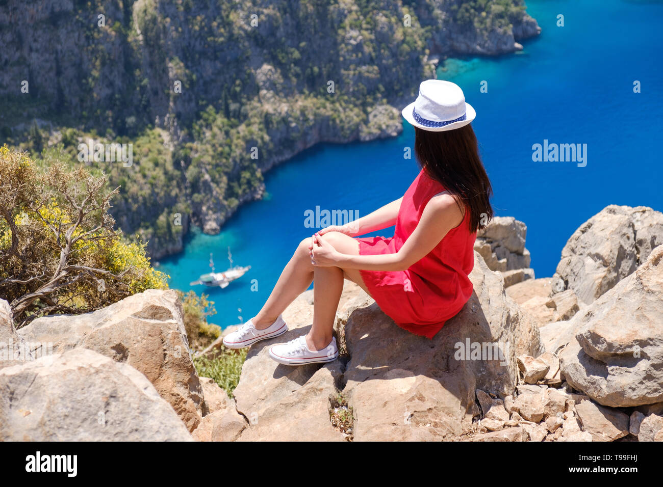 La Turquie Oludeniz, le paysage, une jeune fille dans une robe rouge regarde la vallée des papillons à partir de ci-dessus, assis sur les rochers Banque D'Images