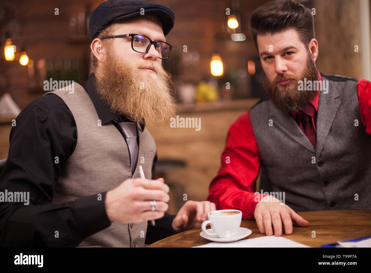 Deux hommes d'affaires prospères ayant une importante réunion à vintage pub. Tasse à café. Les hommes attrayants. Le travail d'équipe. Banque D'Images