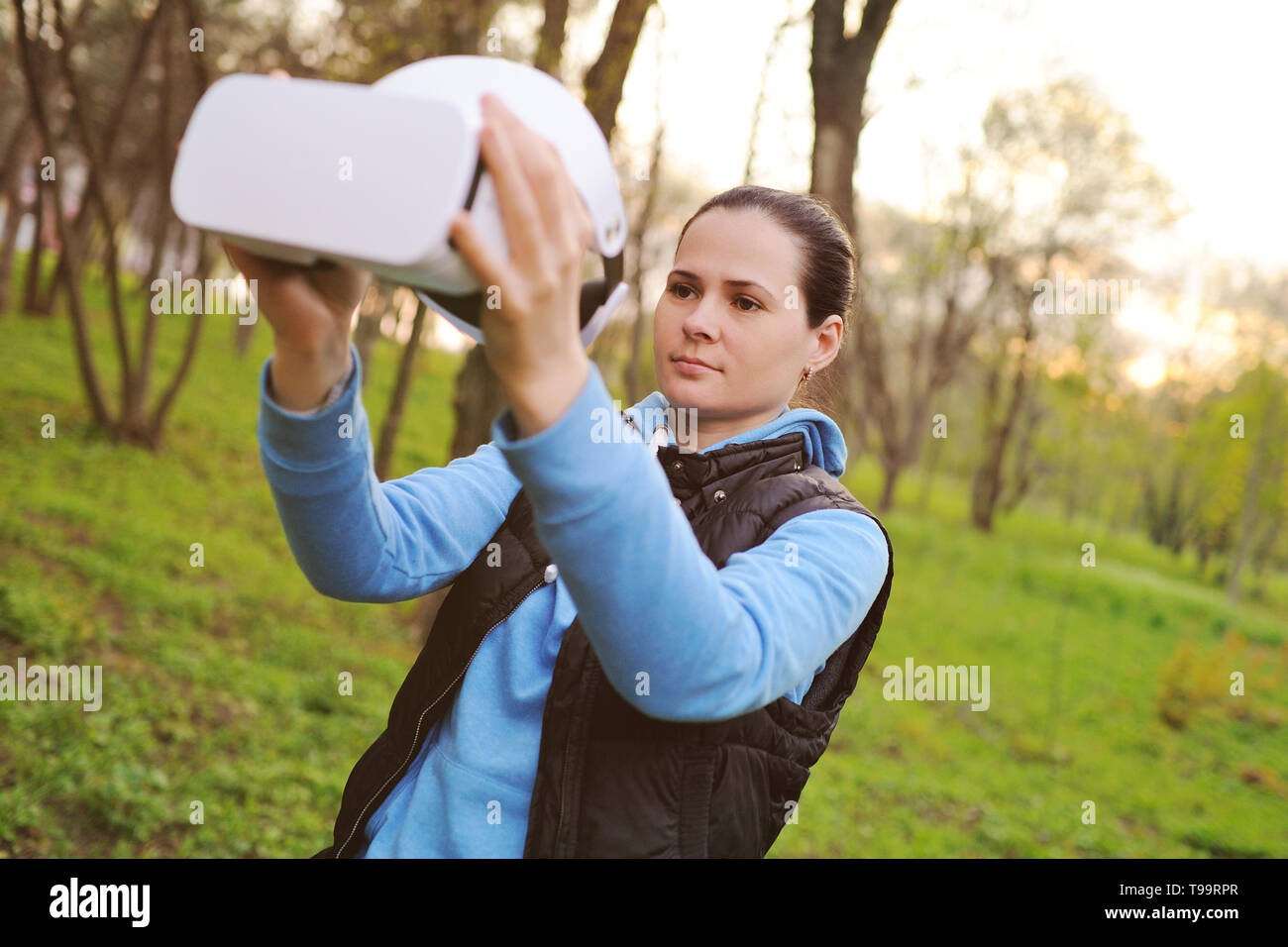 Fille avec des lunettes la réalité virtuelle sur le fond de verdure et parc Banque D'Images