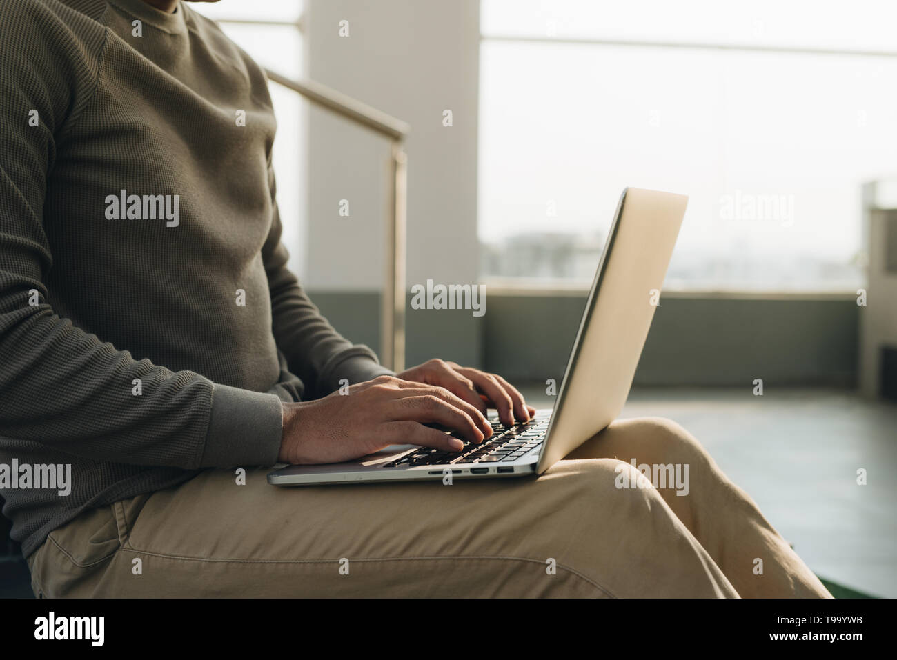 Un homme assis à l'ordinateur portable sur ses genoux. Banque D'Images
