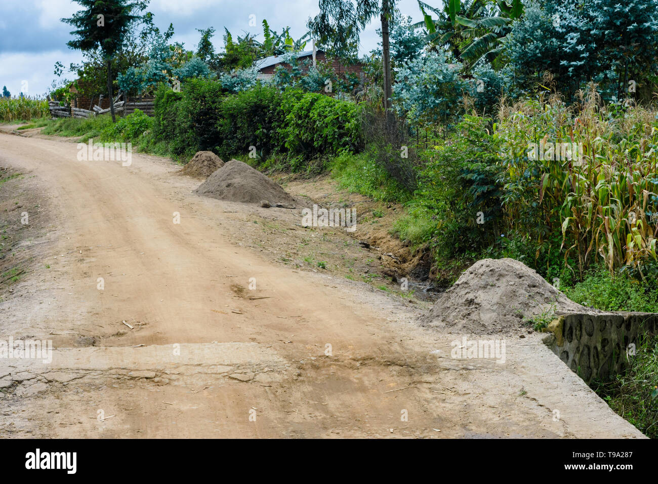 Le sable de construction creusée d'une rivière et entassé dans des piles pour la vente pour la construction sur le bord d'une route de terre dans un village du Malawi Banque D'Images