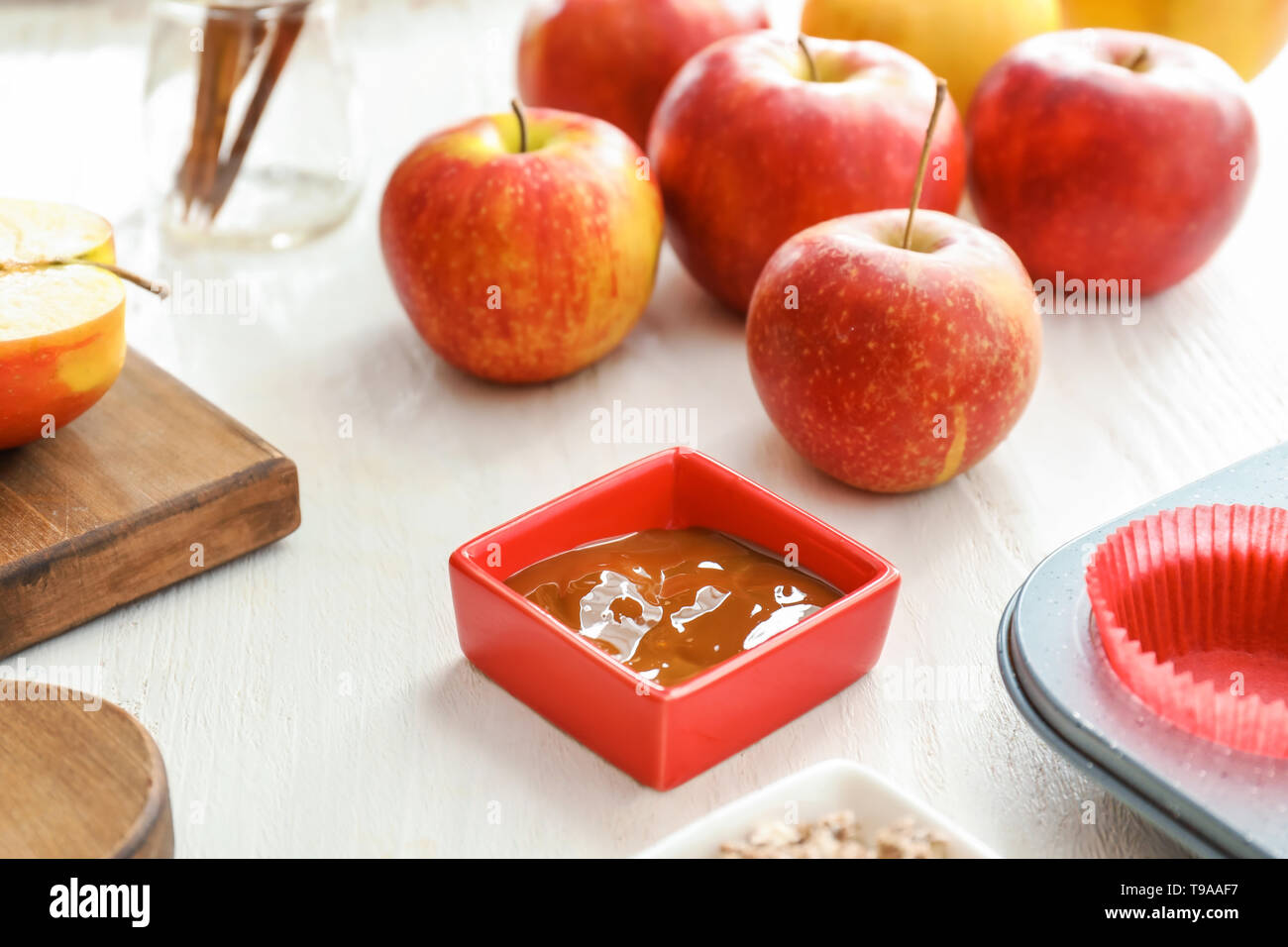 Des pommes mûres et le bol de sauce sur tableau blanc Banque D'Images