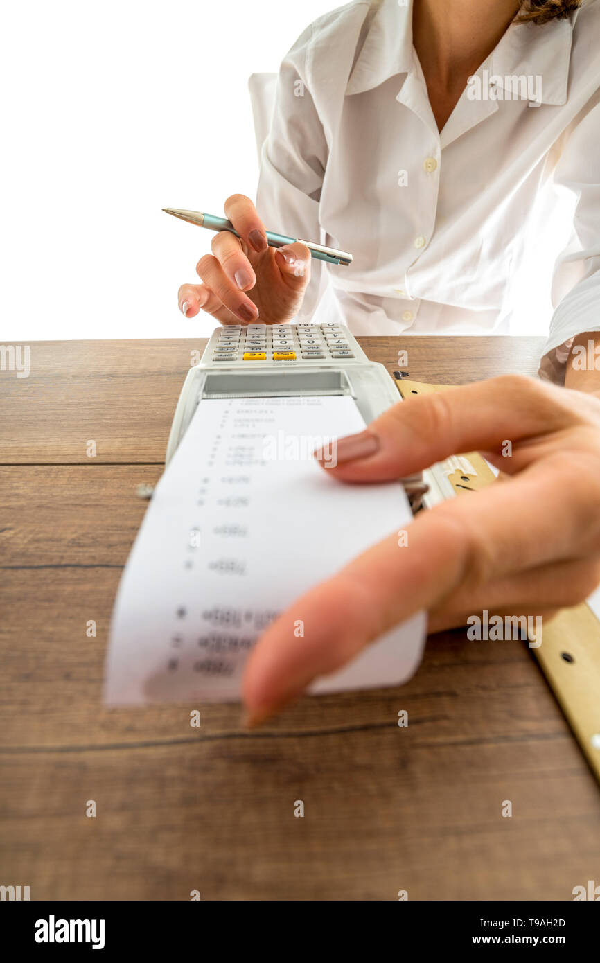 Femme sa comptabilité sur une machine avec un ajout manuel low angle view passé la bande de papier imprimé à ses doigts sur les touches numériques. Banque D'Images