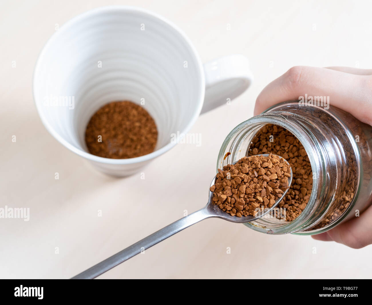 Près de cuillère à café instantané avec bol en verre sur mug sur la table marron clair Banque D'Images