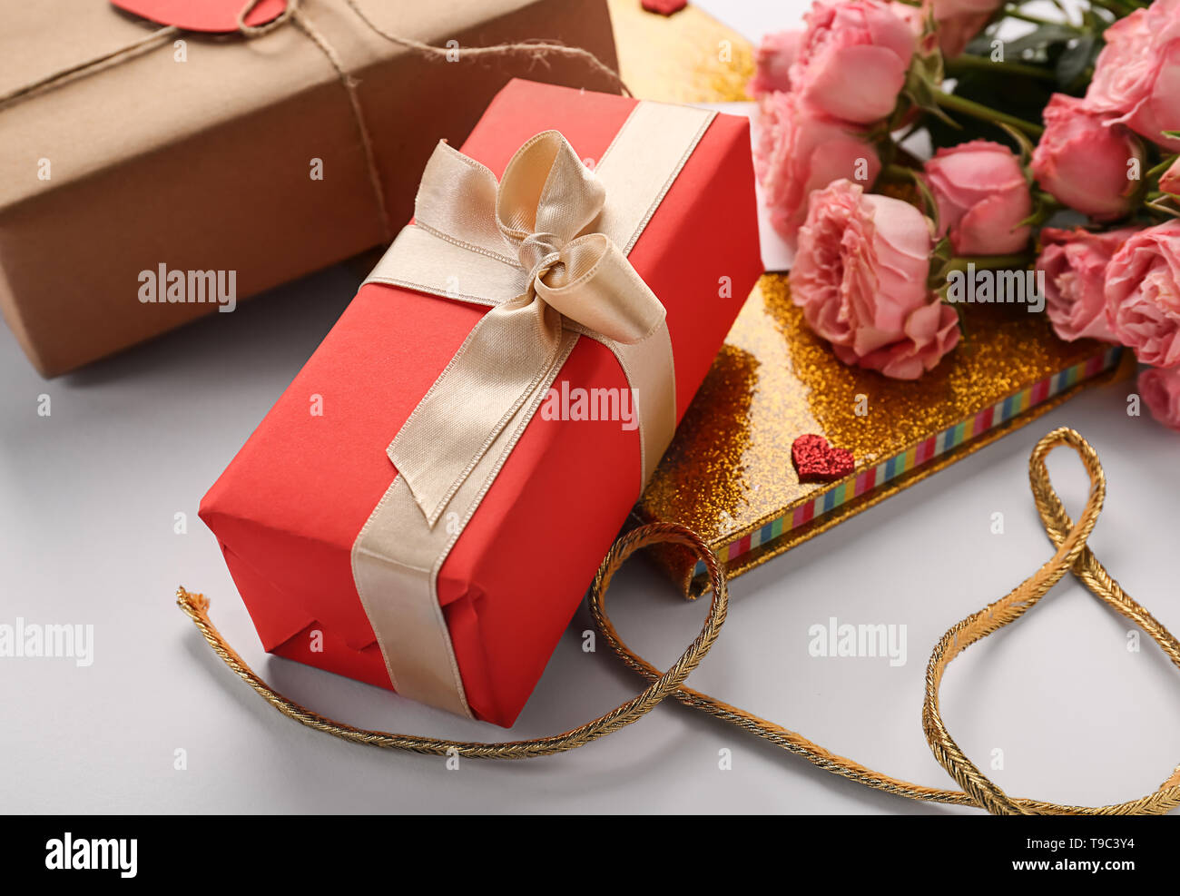 Beau cadeau avec l'ordinateur portable d'or et de roses sur la table. Valentines Day celebration Banque D'Images