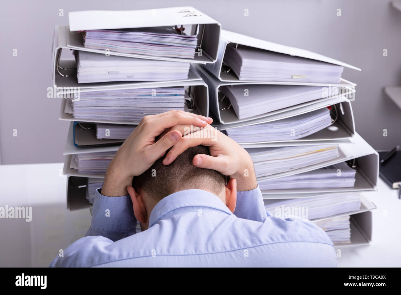 Vue arrière du souligné Businesswoman Pointing en face de dossiers empilés Banque D'Images