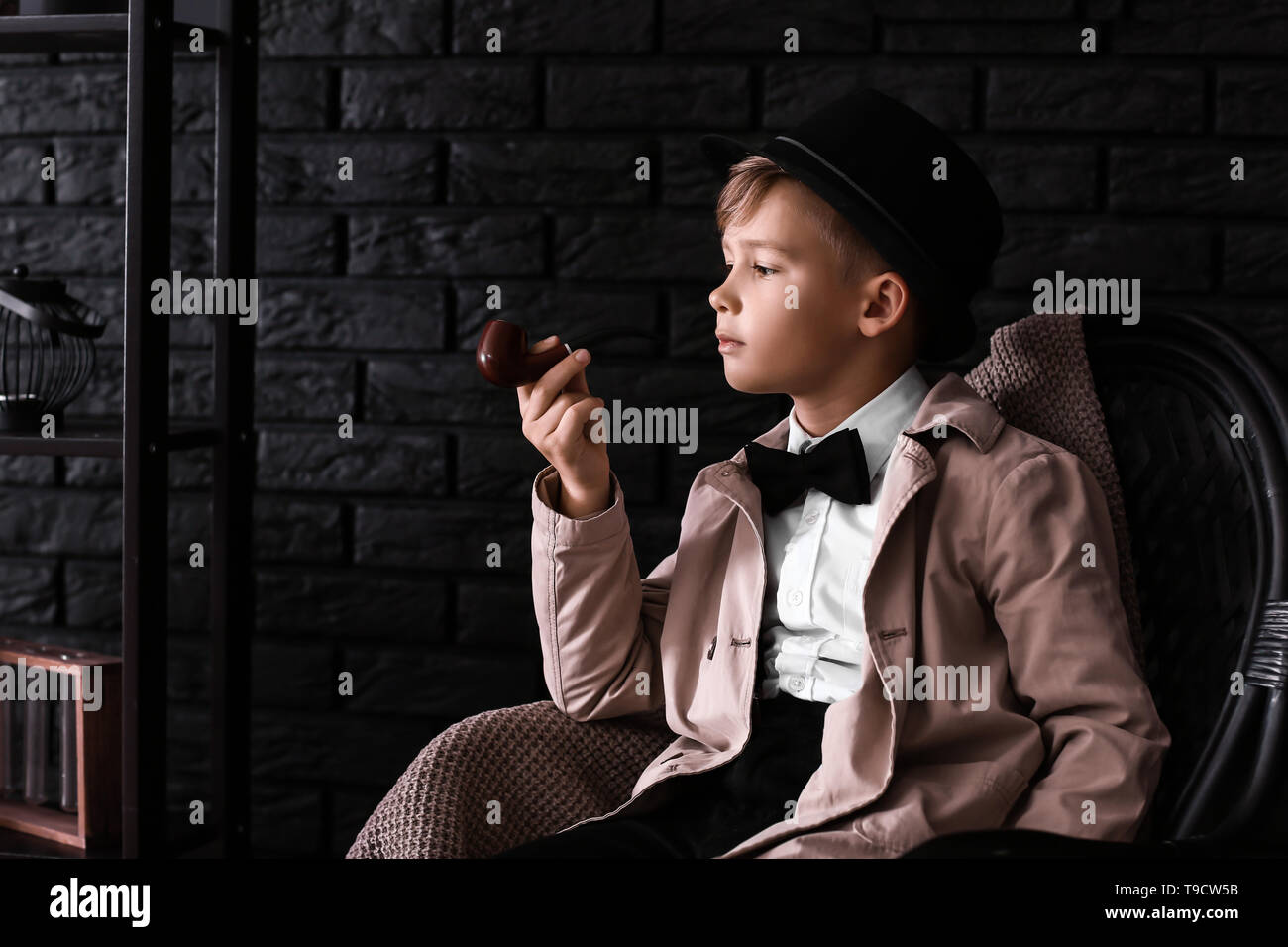 Cute little detective avec tuyau sitting in armchair Banque D'Images